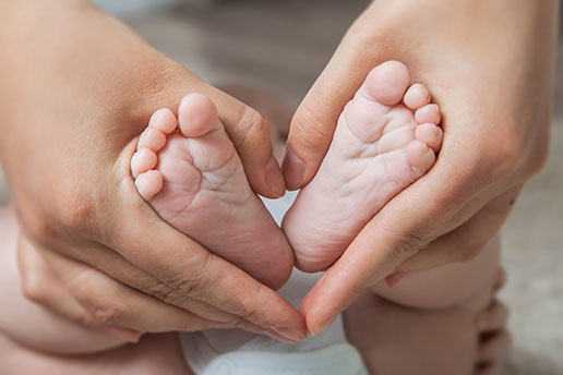 Baby feet held in a heart shape.