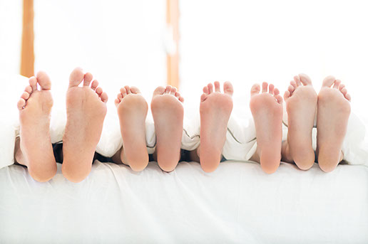 Family of feet in a bed.